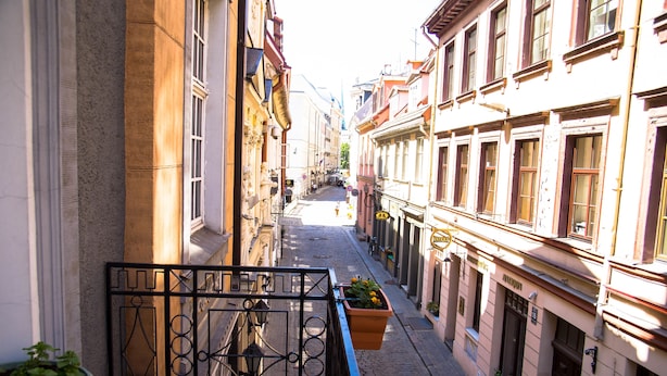 A narrow street with buildings on either side, a metal gate, and potted plants. - Boutique Hotel KRISTOFS (Riga)