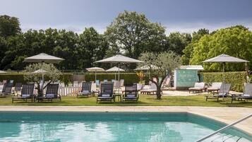 Una piscina techada, una piscina al aire libre de temporada, sombrillas