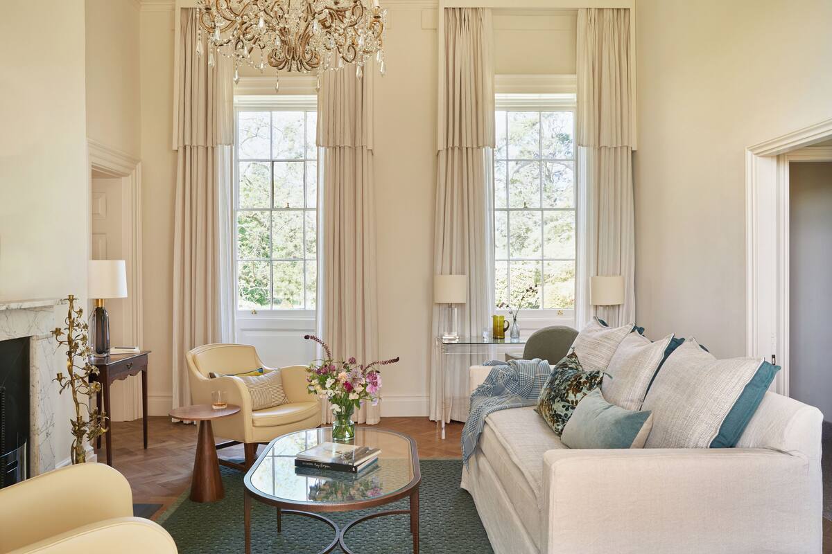 A well-lit living room with a sofa, armchairs, a coffee table, and a fireplace.