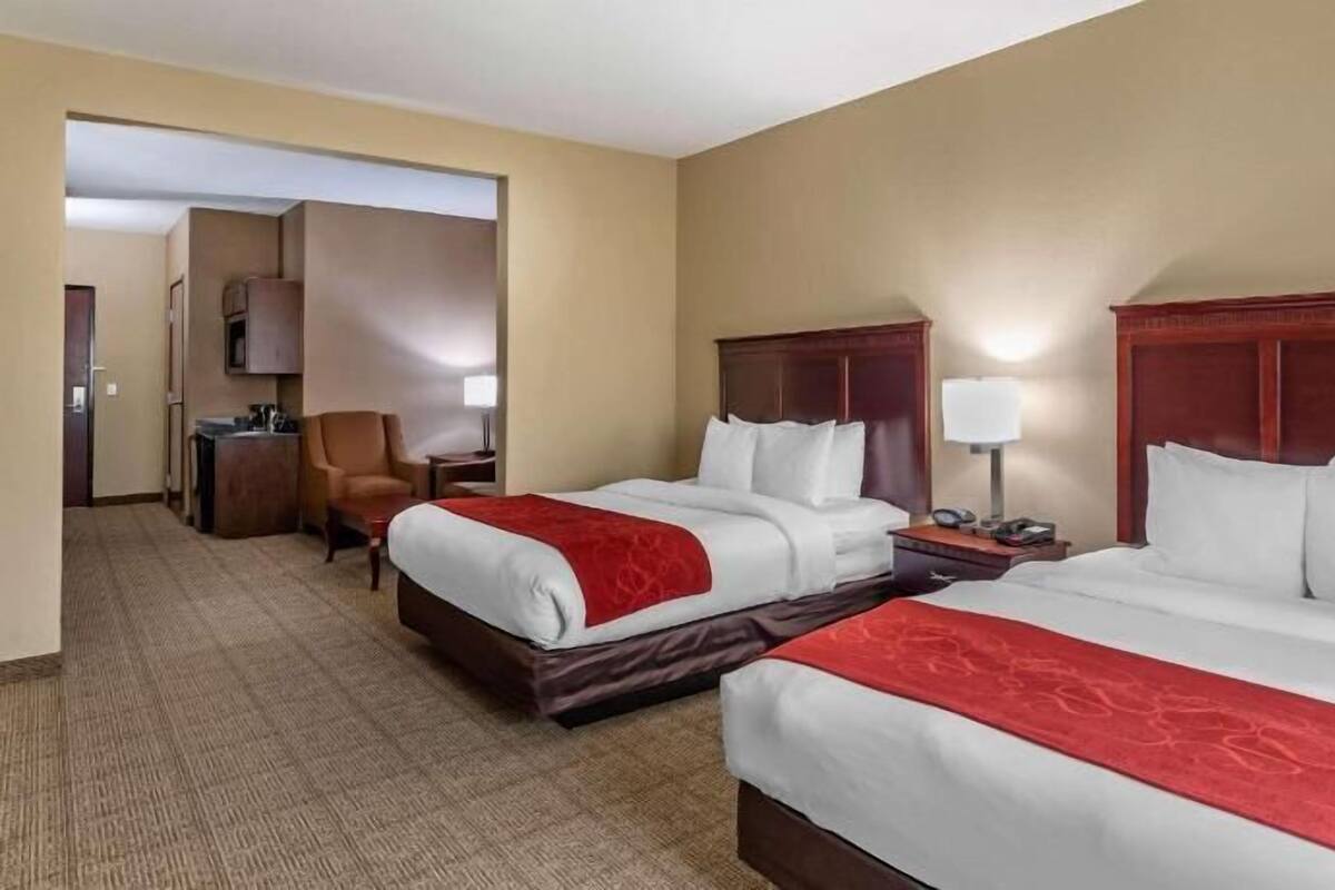 Ein Hotelzimmer mit zwei Betten, einem Schreibtisch, einem Stuhl und einem Fernseher.