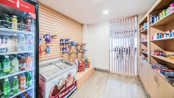 A grocery store interior with refrigerated beverages, snack aisles, and a freezer section.