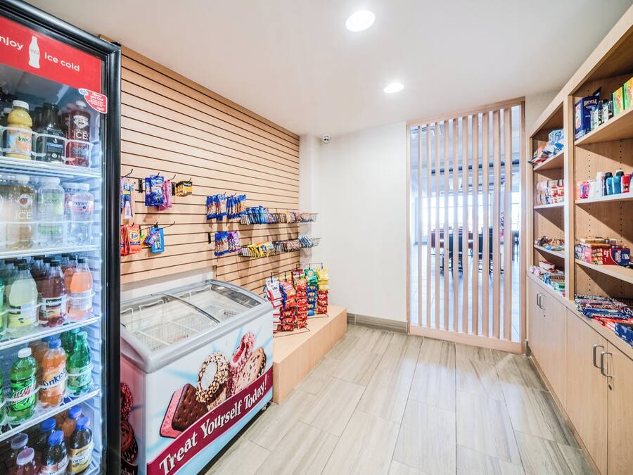 A grocery store interior with refrigerated beverages, snack aisles, and a freezer section.