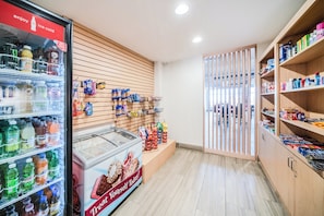Interior de un supermercado con bebidas refrigeradas, pasillos de aperitivos y una sección de congelados.