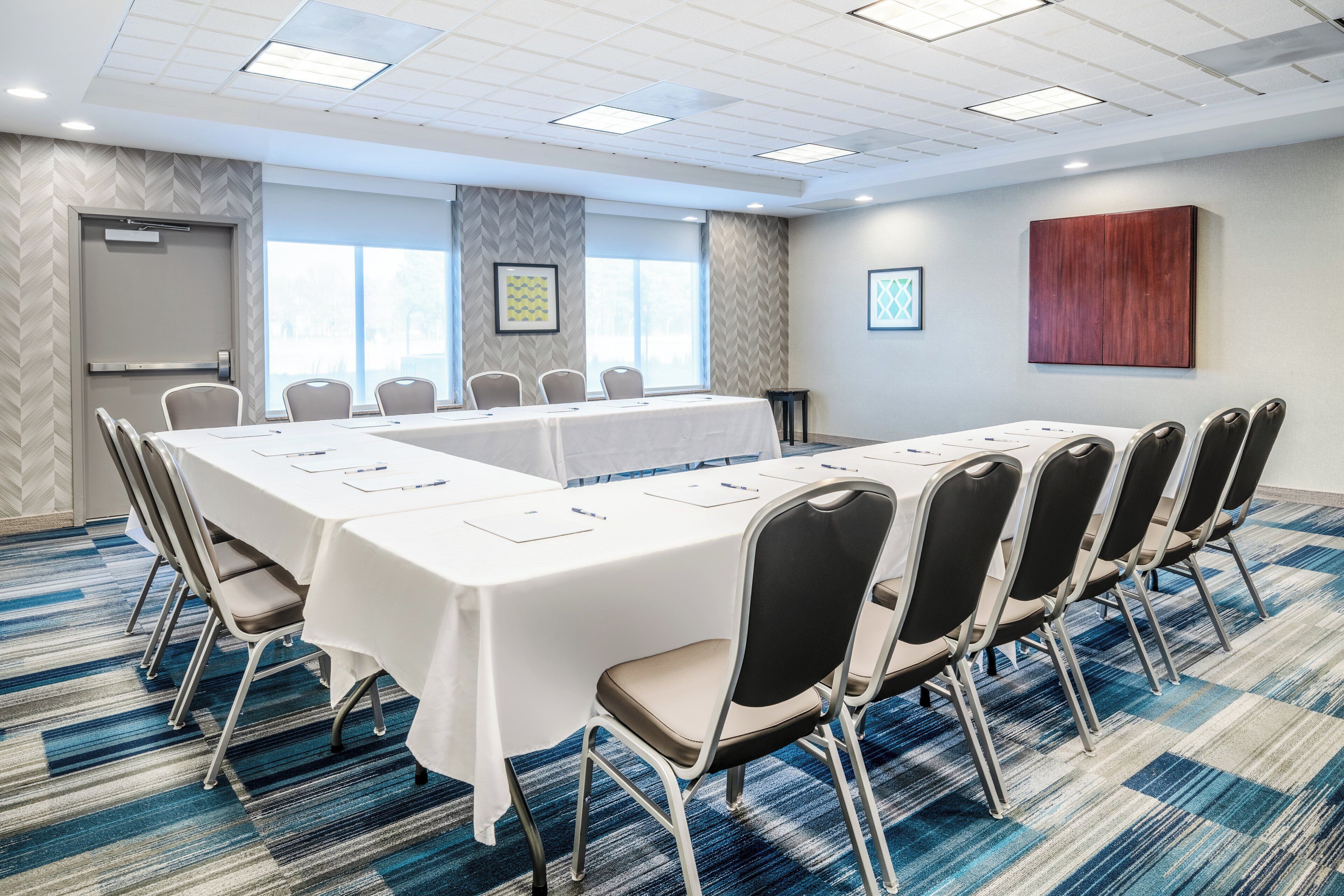 A conference room with a long table, chairs, and a carpeted floor.