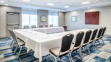 A conference room with a long table, chairs, and a carpeted floor.