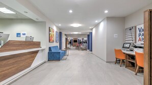 Ein Hotel-Rezeptionsbereich mit einem Holzbüro, blauen Sitzgelegenheiten und einem Computerarbeitsplatz.