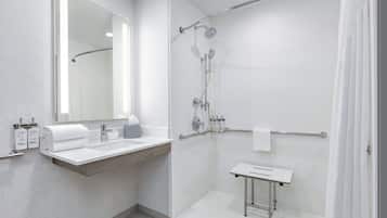 Un baño moderno con ducha, lavamanos y espejo.