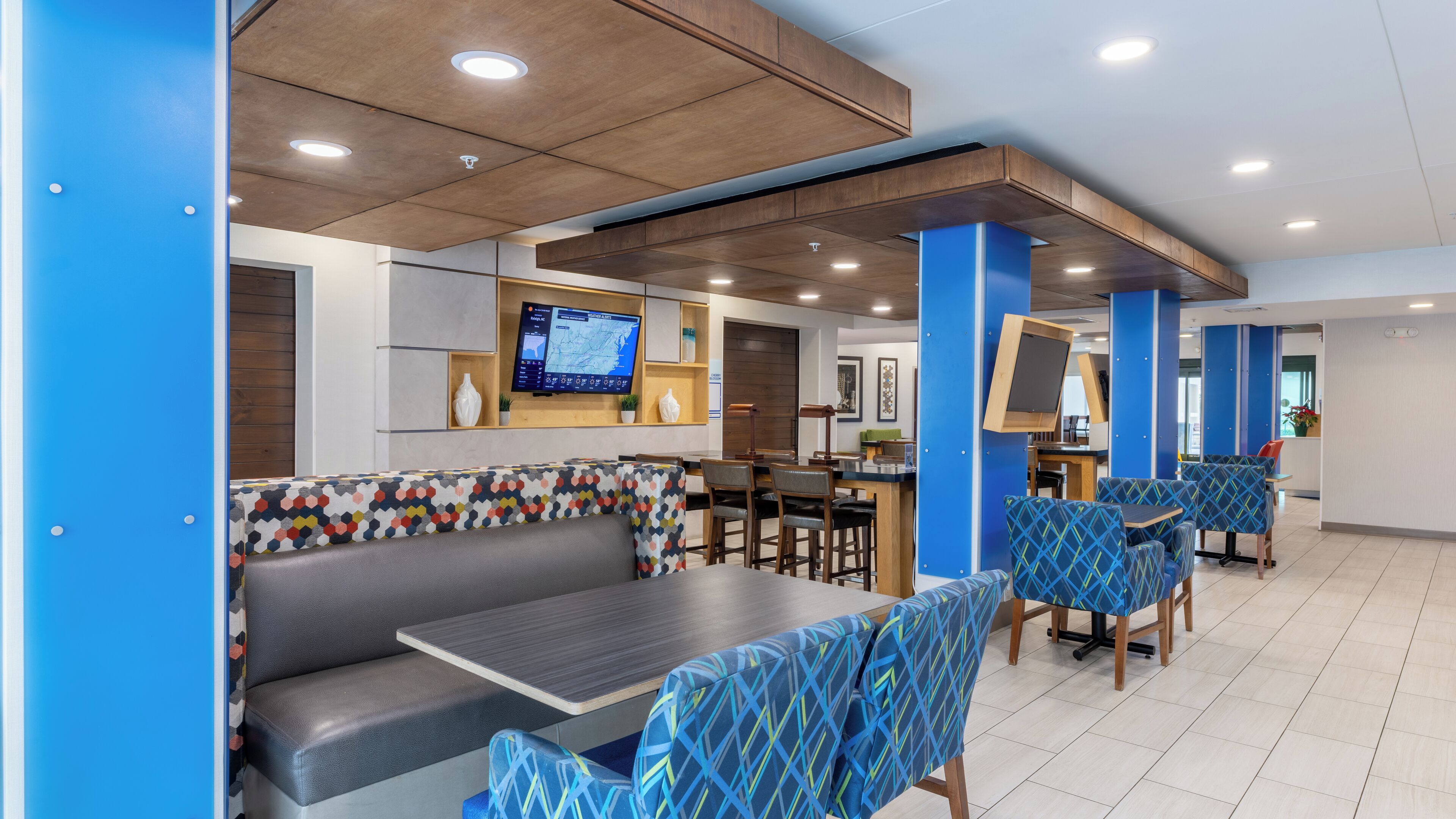 Un restaurante moderno con cabinas, mesas y una gran pantalla de televisión que muestra un mapa.