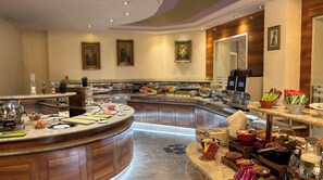 A modern kitchen with a curved island, equipped with various cooking appliances and a buffet setup.