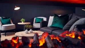 A modern living room with a round coffee table, two armchairs, a sofa, and a small side table with a plant. - Gr8 Hotel Sevenum (Sevenum)