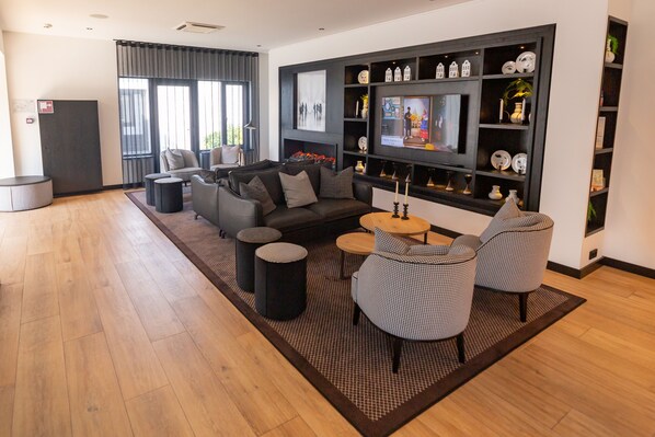 Una sala de estar moderna con un sofá, sillones, una mesa de centro y un televisor montado en una pared negra.