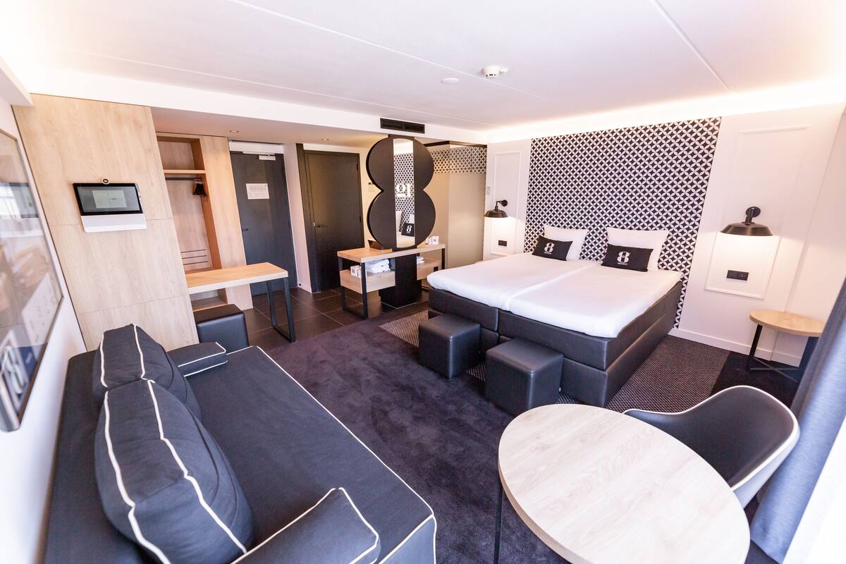 Une chambre d’hôtel moderne avec un lit, un canapé et une petite table.