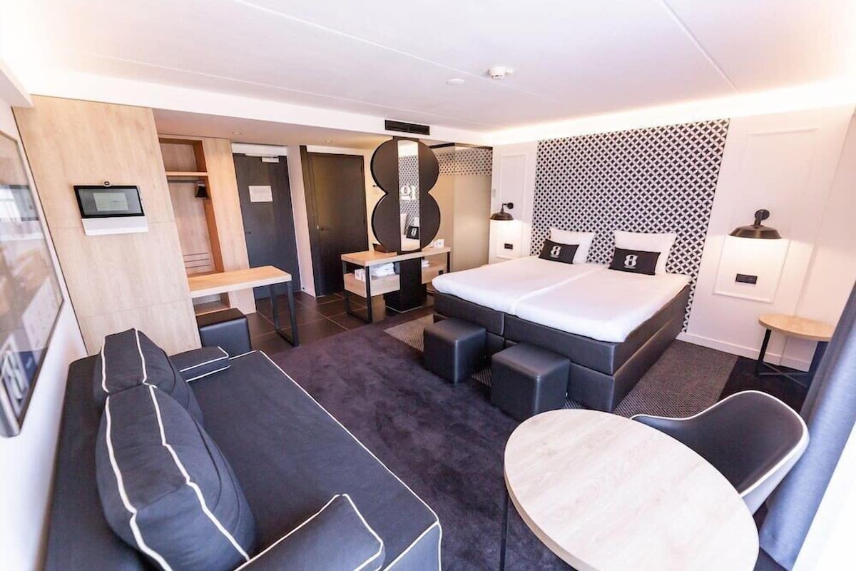 Une chambre d’hôtel moderne avec un lit, un canapé et une petite table.