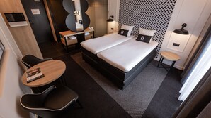 A modern hotel room with a double bed, a desk with a chair, a small round table, and a mirror. - Gr8 Hotel Sevenum (Sevenum)