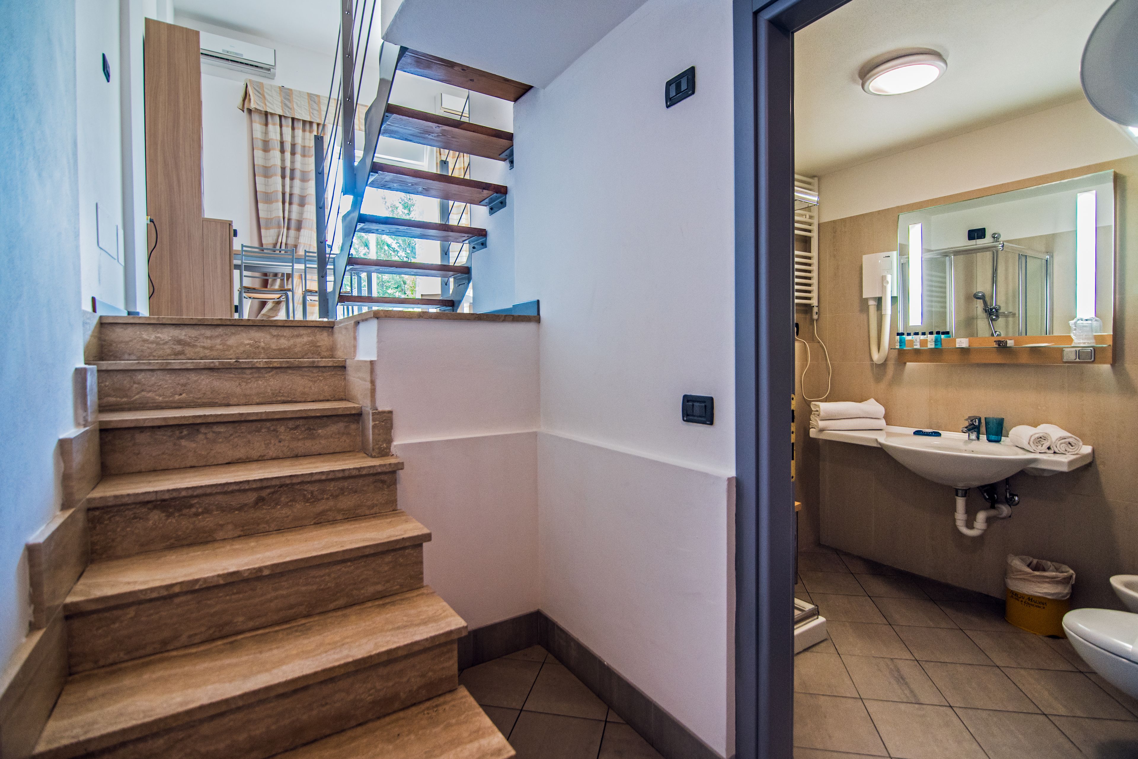 A staircase leading to a room with a bathroom that includes a sink, mirror, and toilet.