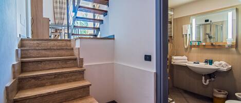 A staircase leading to a room with a bathroom that includes a sink, mirror, and toilet.