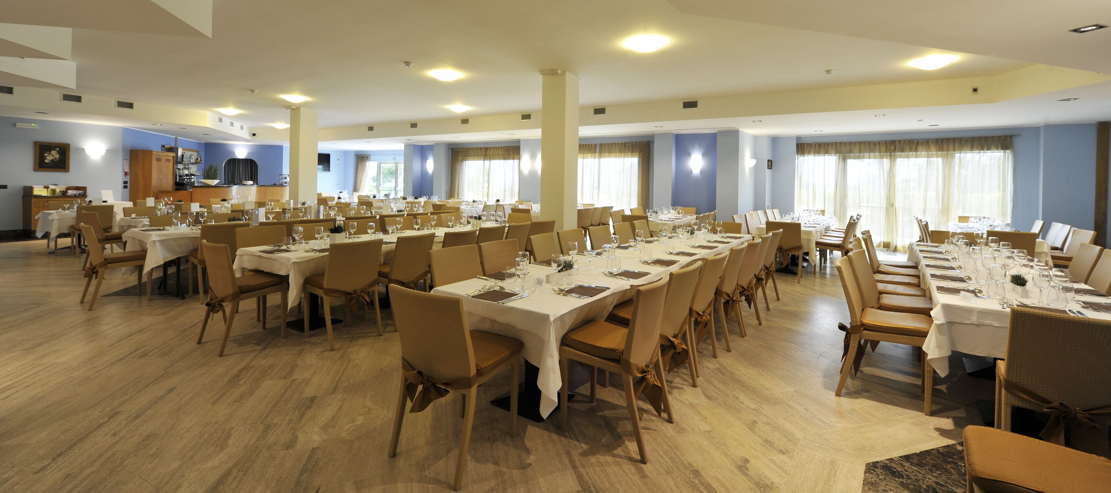 A large conference room with multiple tables and chairs, equipped with nameplates and table settings.