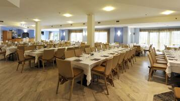 A large conference room with multiple tables and chairs, equipped with nameplates and table settings.