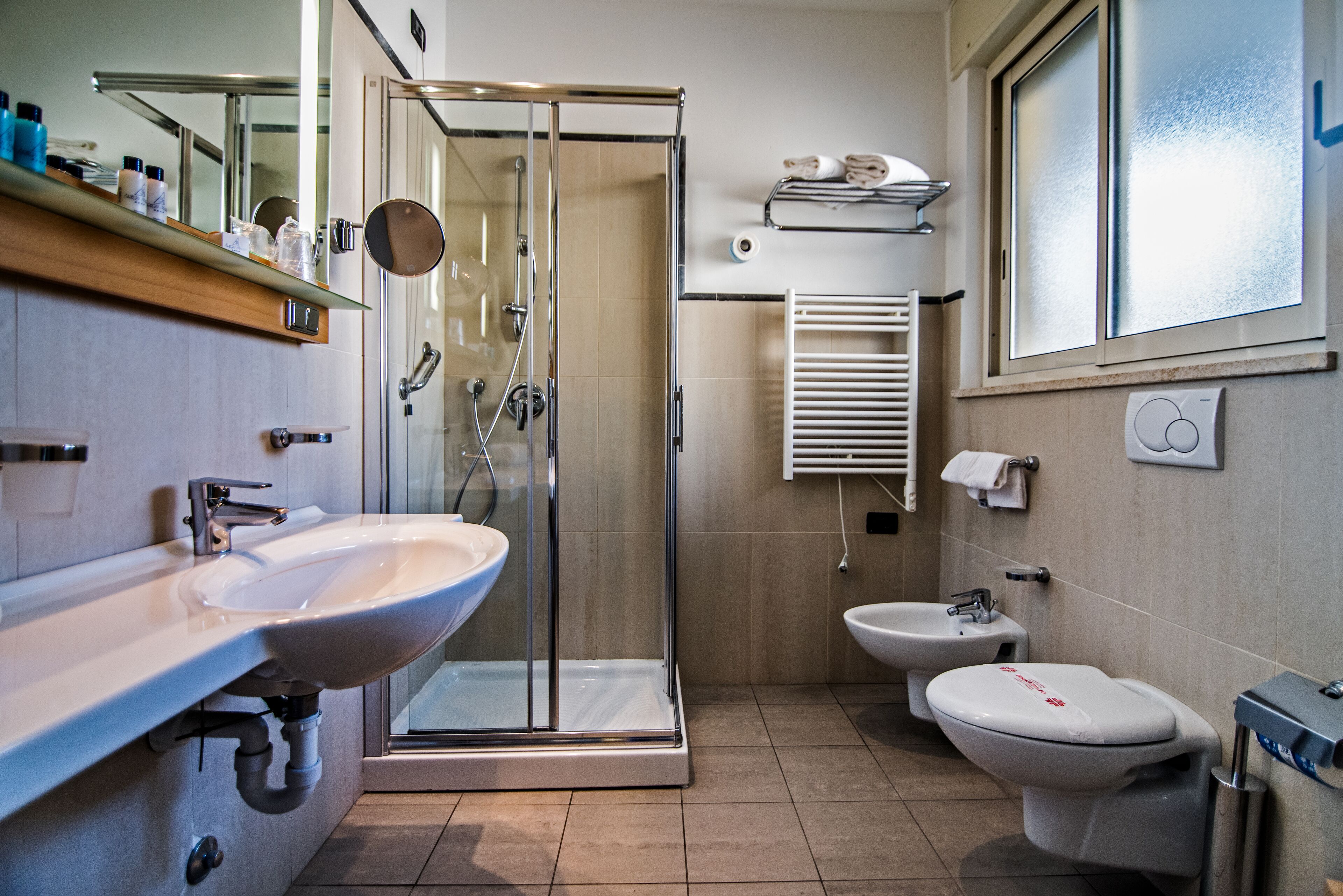 A modern bathroom with a glass-enclosed shower, a sink, a bidet, and a toilet.