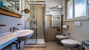 A modern bathroom with a glass-enclosed shower, a sink, a bidet, and a toilet.