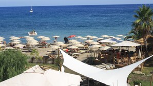 Een strandcafé met terras en parasols, met uitzicht op zee.
