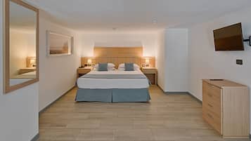 Une chambre à coucher moderne, avec un lit, des tables de chevet, une commode, un téléviseur et un tableau encadré au mur.