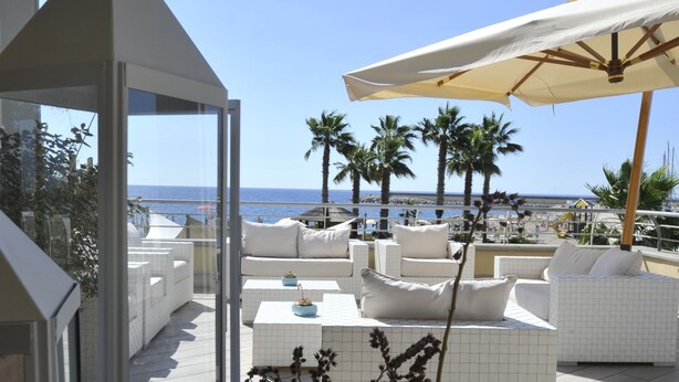 Een terras op het dak met witte meubels, een tafel met kaarsen en uitzicht op zee.
