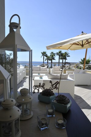 Una terraza en la azotea con muebles blancos, una mesa con velas y vistas al mar.