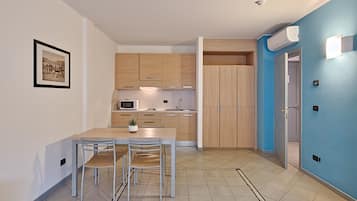 Una cocina moderna con armarios de madera, una mesa de comedor con sillas, un microondas y una pequeña planta en maceta.