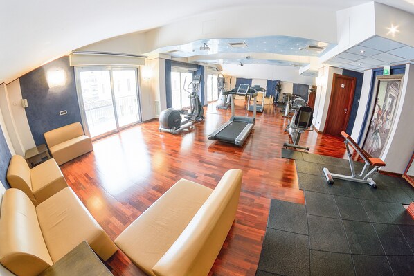 A gym with exercise equipment, seating areas, and a large window providing natural light.