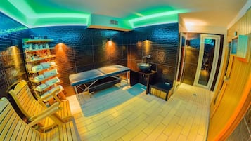 Experience a serene spa retreat with a massage table, large bowl sink, and sauna area.