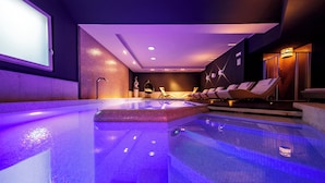 Una piscina interior moderna con zona de estar y pantalla de proyección.