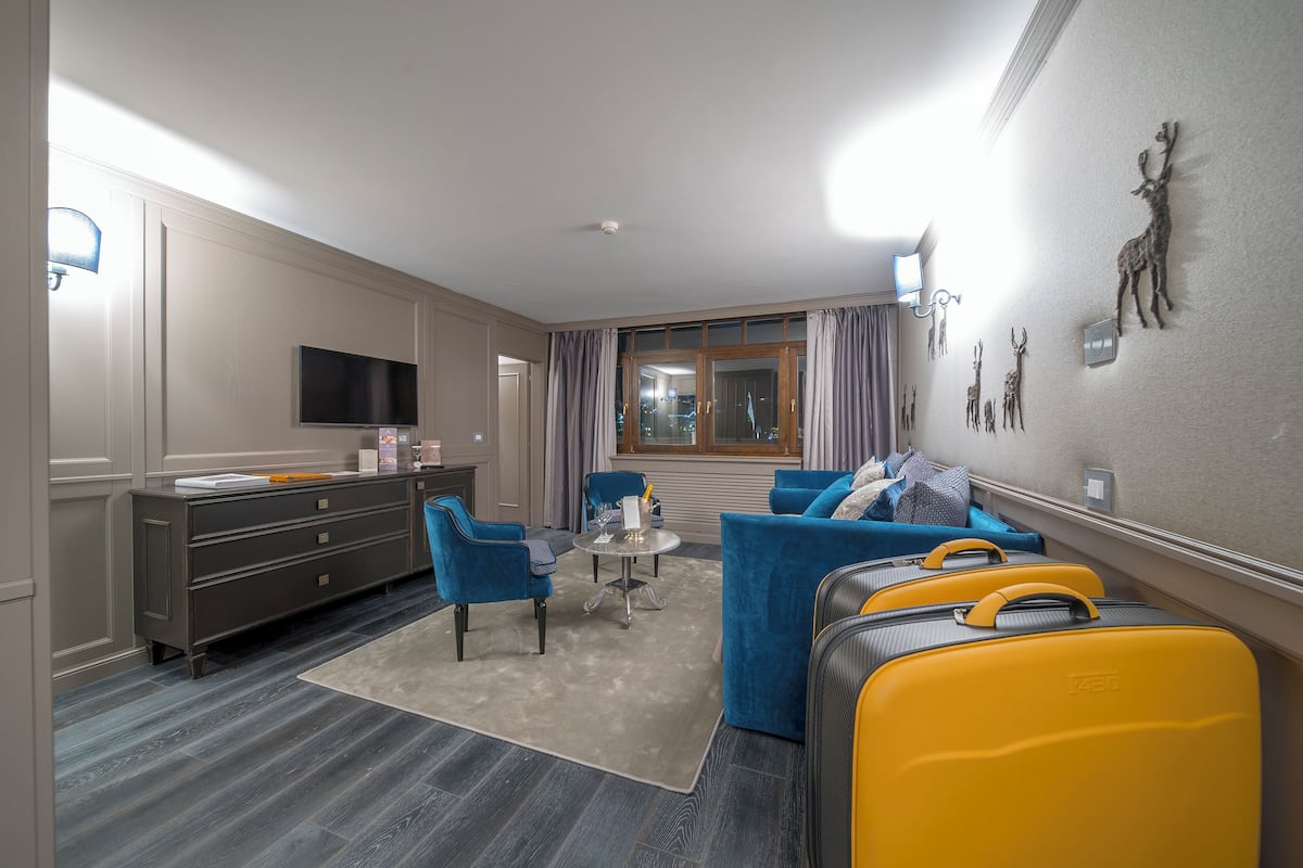 Ein Hotelzimmer mit Sofa, Sesseln, Schreibtisch, Fernseher und Gepäck.