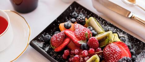 A breakfast setting with a fruit platter, coffee cups, and a dessert plate.