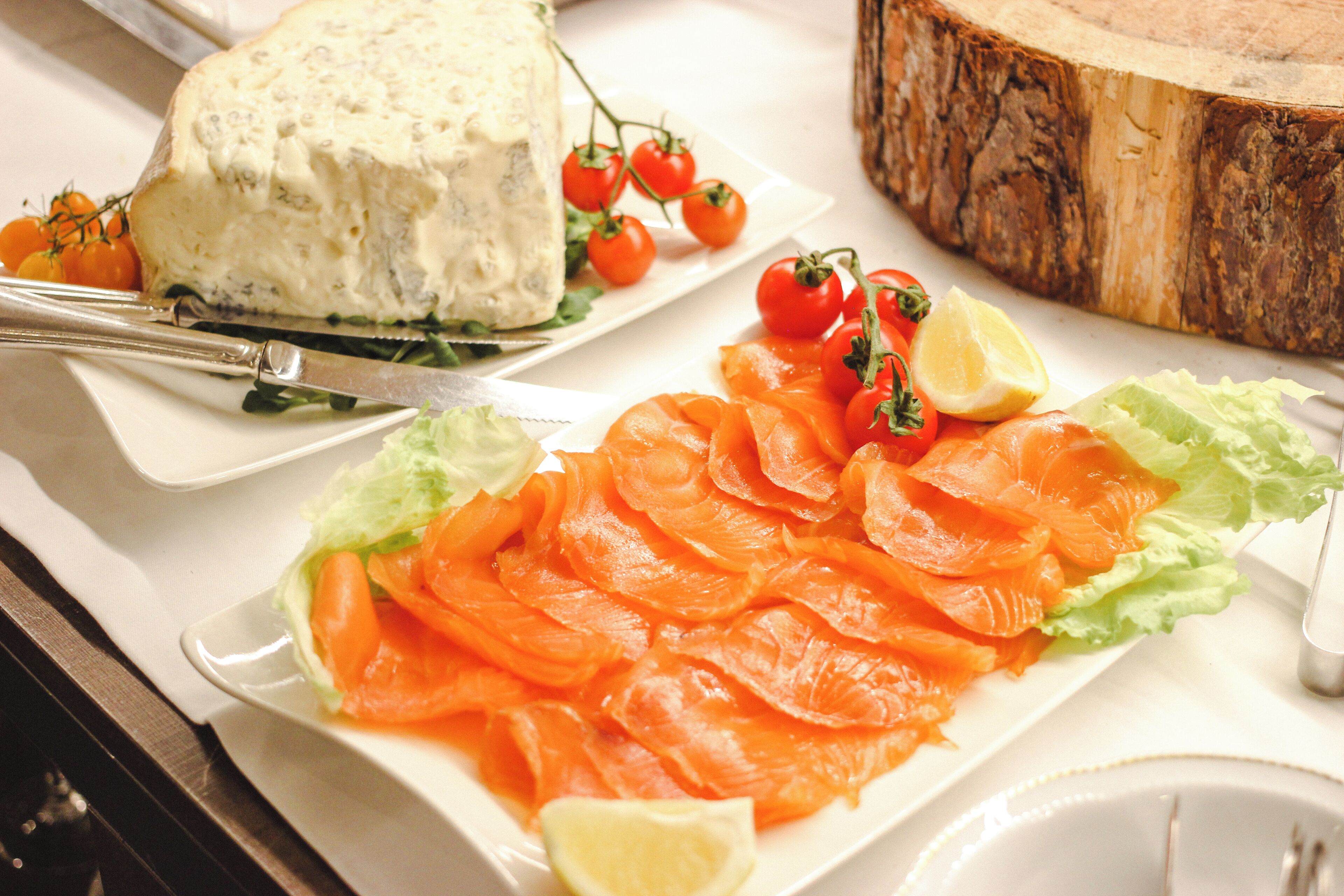 A plate of smoked salmon with cherry tomatoes and a wedge of lemon.