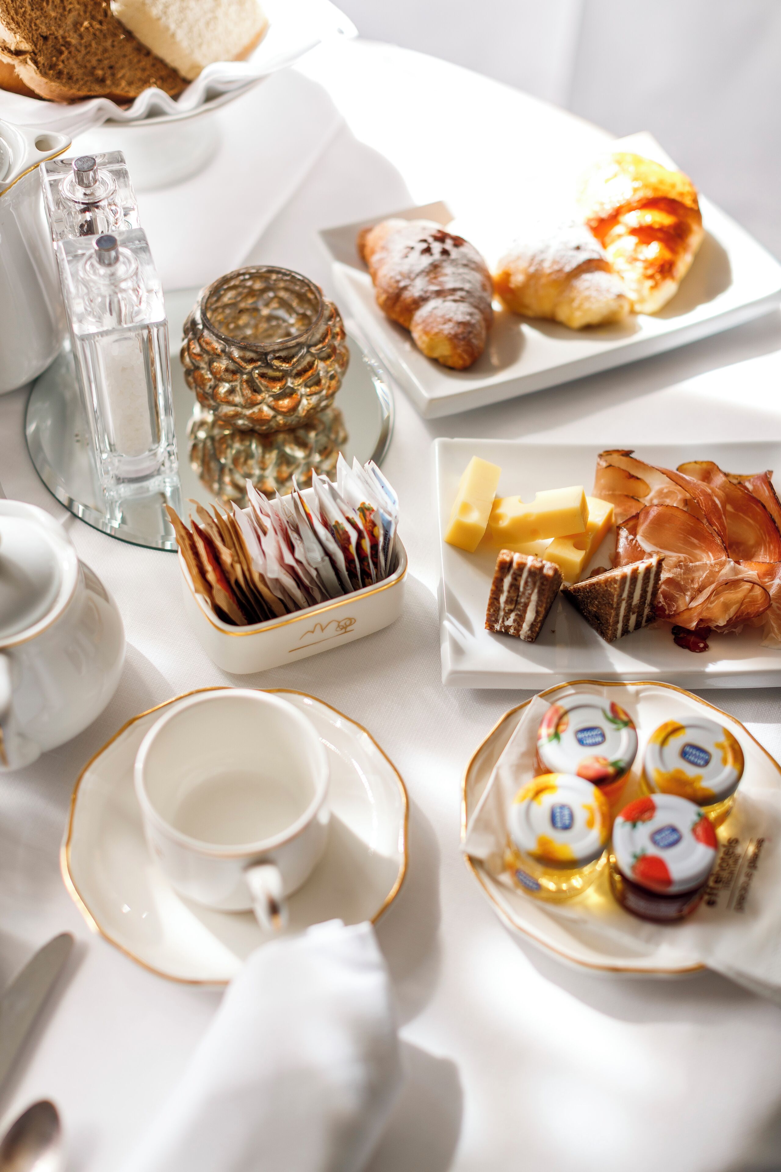 Un desayuno con diferentes alimentos, una tetera, tazas y un tarro de vidrio.