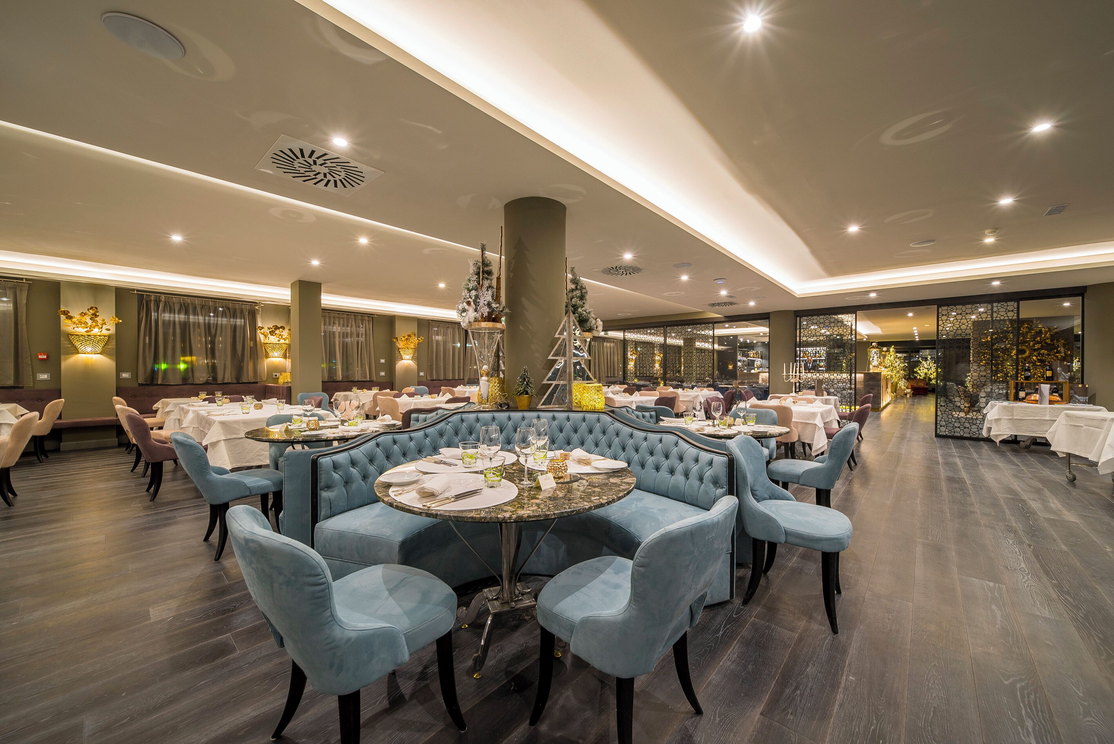 Un restaurante con mesas redondas, sillas tapizadas en azul y una columna central.