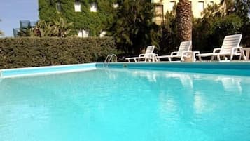 Una piscina al aire libre, sombrillas, tumbonas