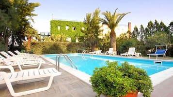 Una piscina al aire libre, sombrillas, tumbonas