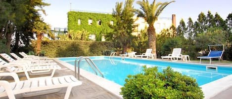 A swimming pool with lounge chairs and a potted plant.