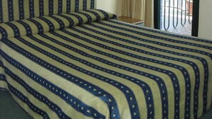 Una habitació d'hotel amb un llit, una finestra amb cortines i quatre quadres emmarcats a la paret.