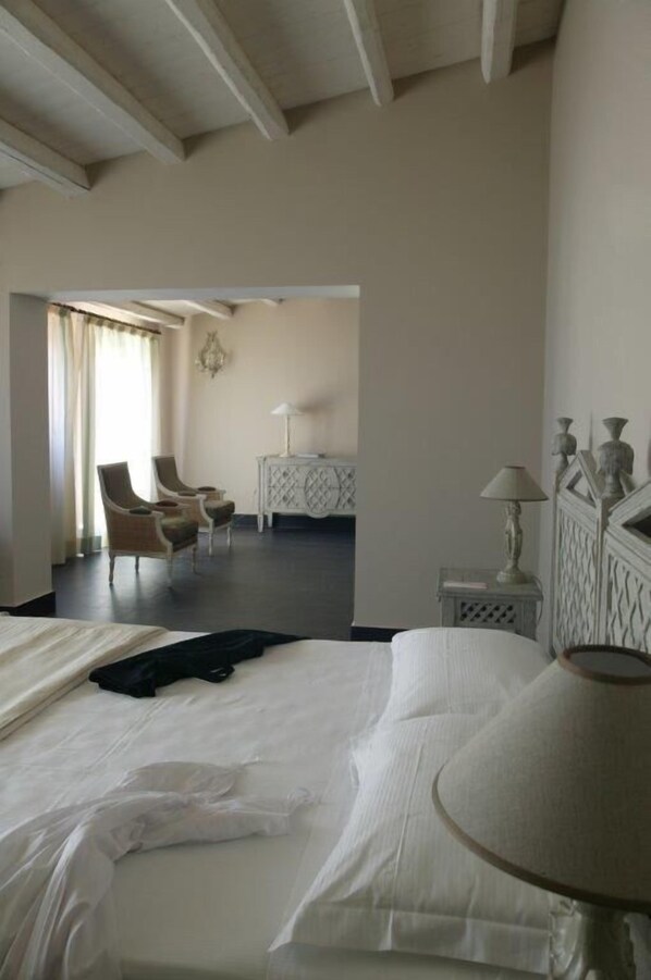 A hotel room with a bed, two chairs, a small table, and a lamp. - Falconara Greenblu Resort (Butera)