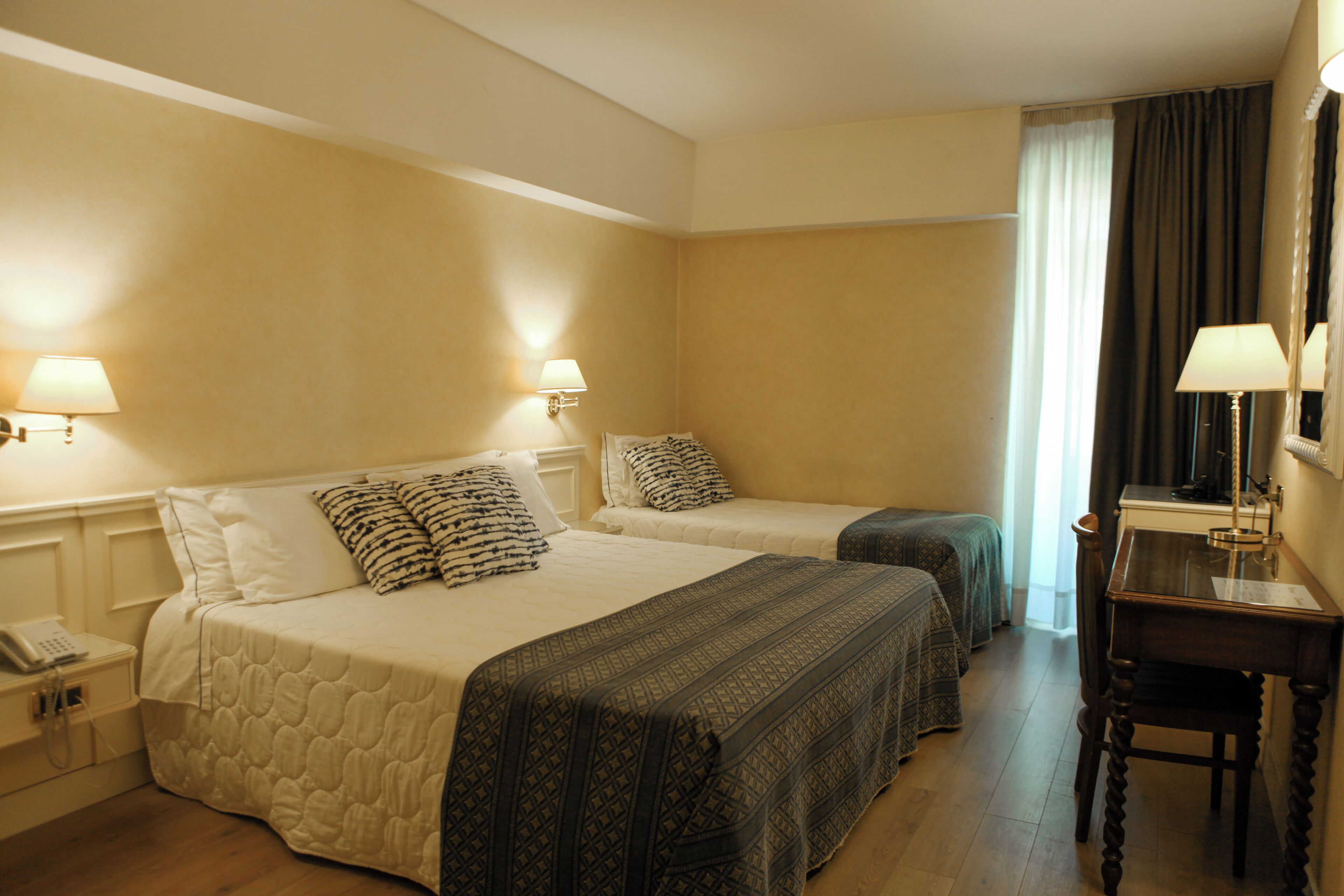 A hotel room with two beds, a desk, and a chair.
