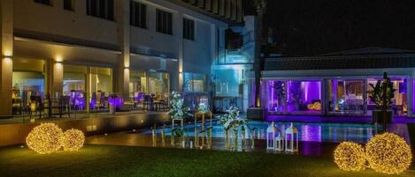 A modern hotel with a pool area, outdoor seating, and decorative lighting.
