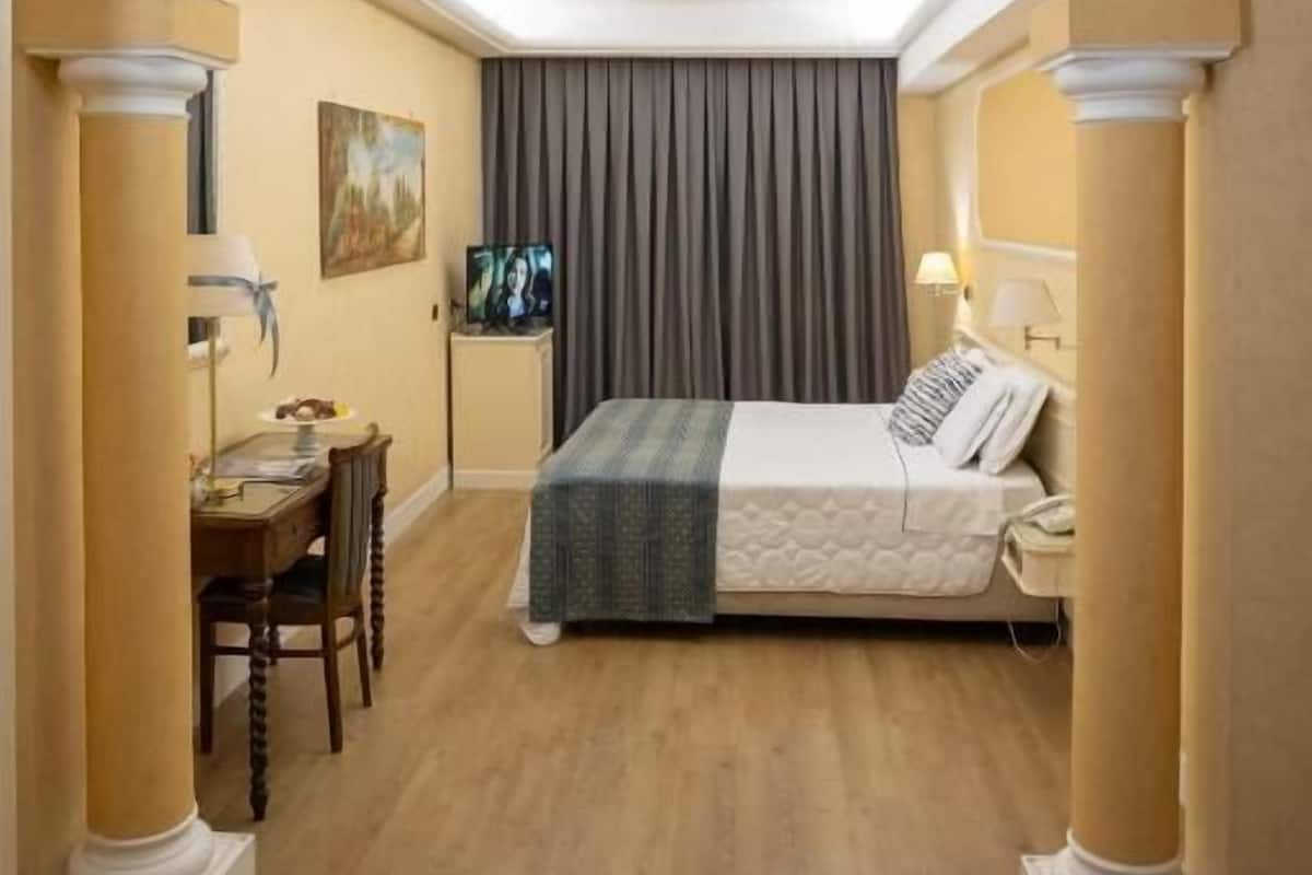Una habitación de hotel con cama, escritorio y televisión.