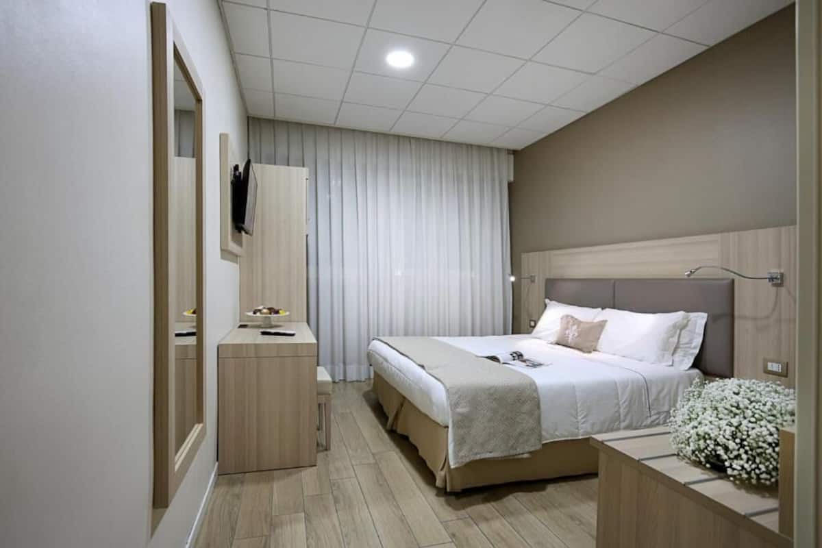 Un dormitorio moderno con cama, mesita de noche y espejo.