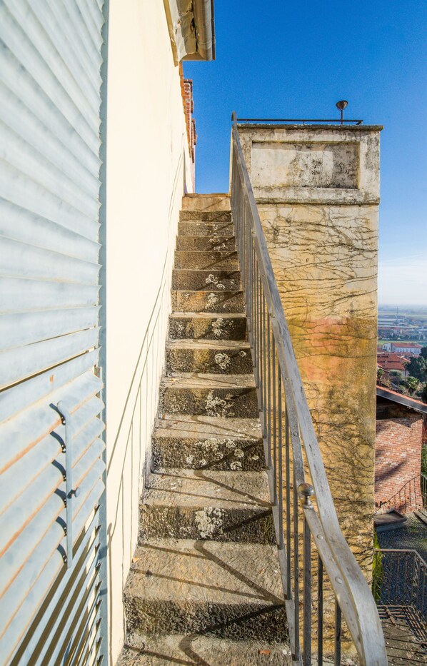 A set of stone stairs with a metal railing leading to a rooftop. - Castello Rosso (Costigliole Saluzzo)
