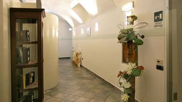 Un passadís amb una biblioteca de fusta, un arranjament floral i un senyal que indica una sortida de seguretat.