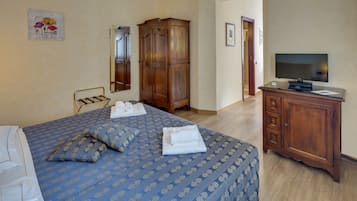 A hotel room with a bed, a wardrobe, a television, and a bathroom visible through an open door.