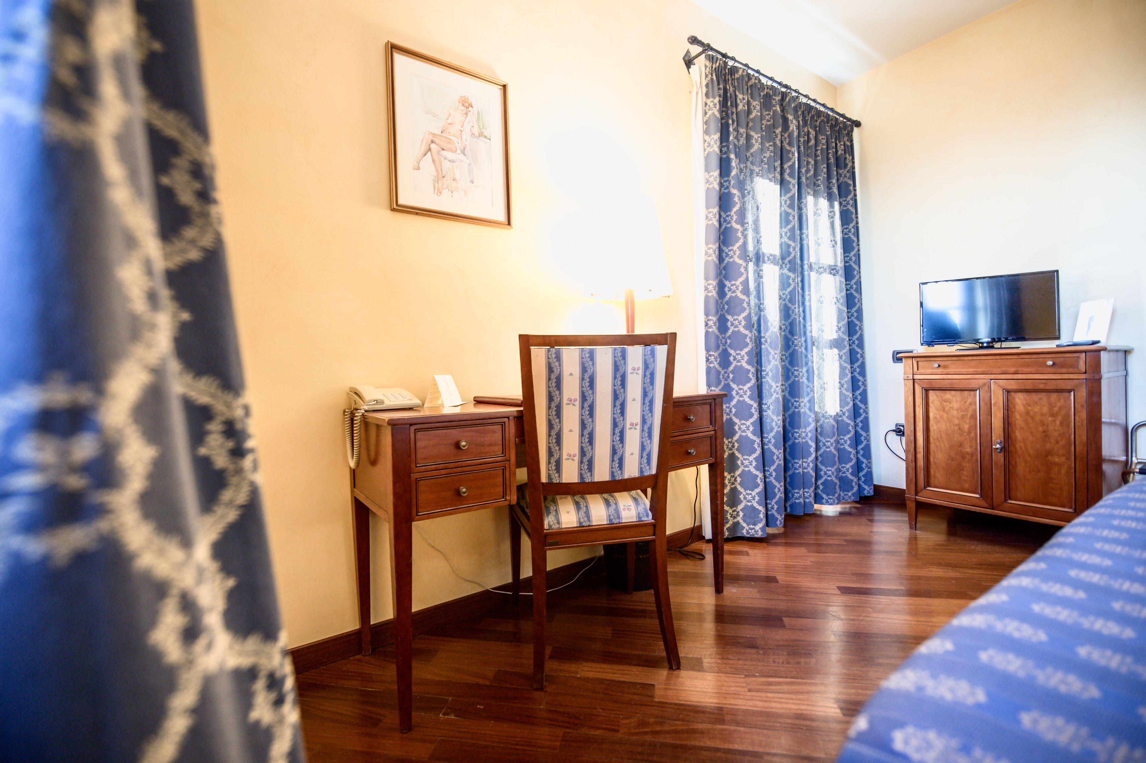 Una habitación de hotel con un escritorio de madera, una silla y un televisor.
